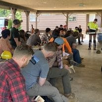 Outdoor workshop attendees seated under pavilion