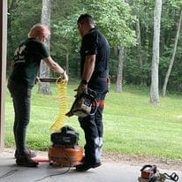 Two people working with tools outside.
