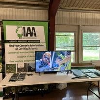 An arboriculture trade show booth with a TV.