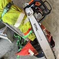 Stihl chainsaw resting on hi-vis jacket with straps