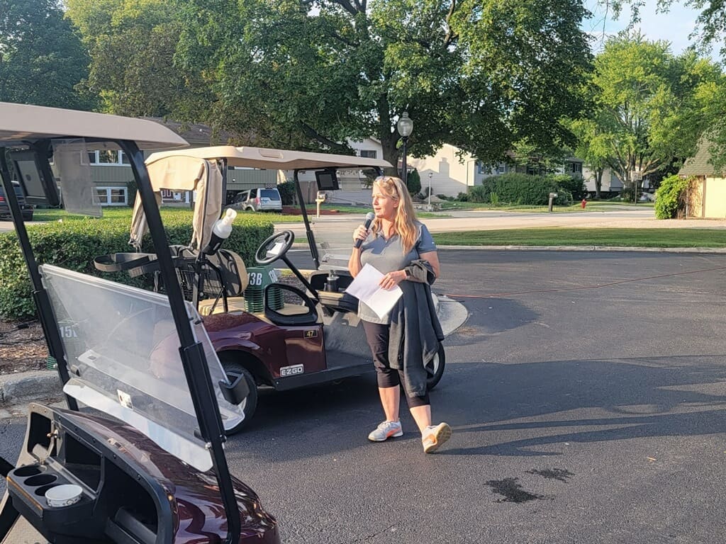 Woman speaking into microphone near golf cart.