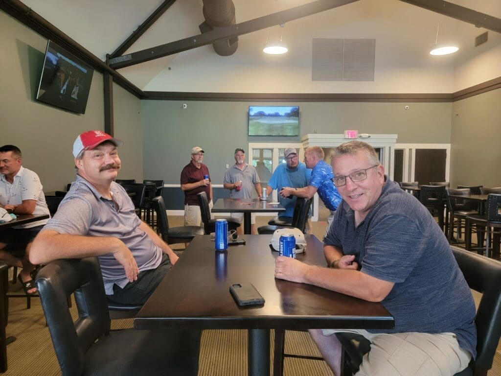 Men gathered around a table in a clubhouse.