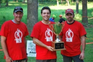 Three men in red shirts hold a trophy.