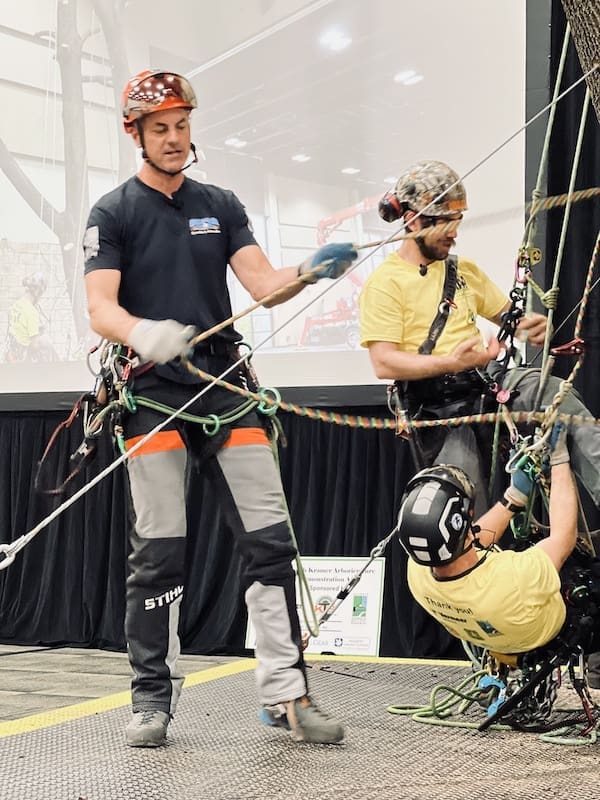 Three men demonstrating tree climbing safety.