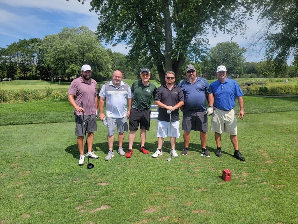 Five men posing on a golf course.