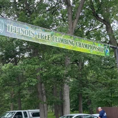 Illinois Tree Climbing Championship banner in forest.