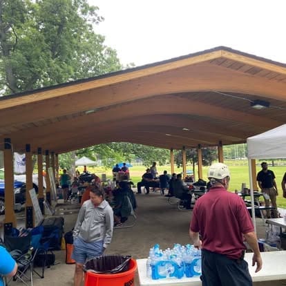 Outdoor gathering under a wooden pavilion.