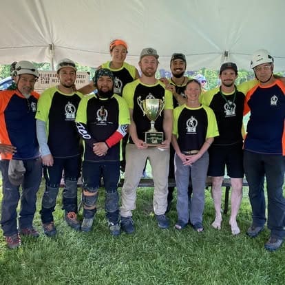 Team posing with trophy under a tent.