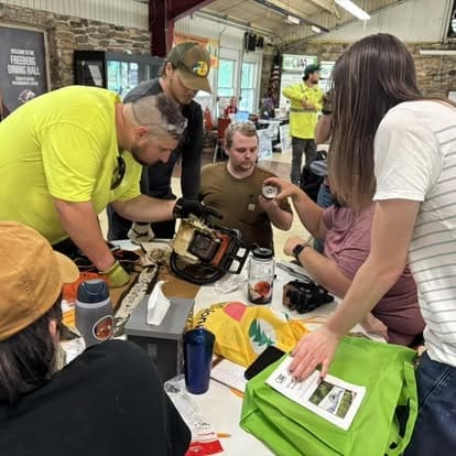 Group inspecting a chainsaw at a workshop.