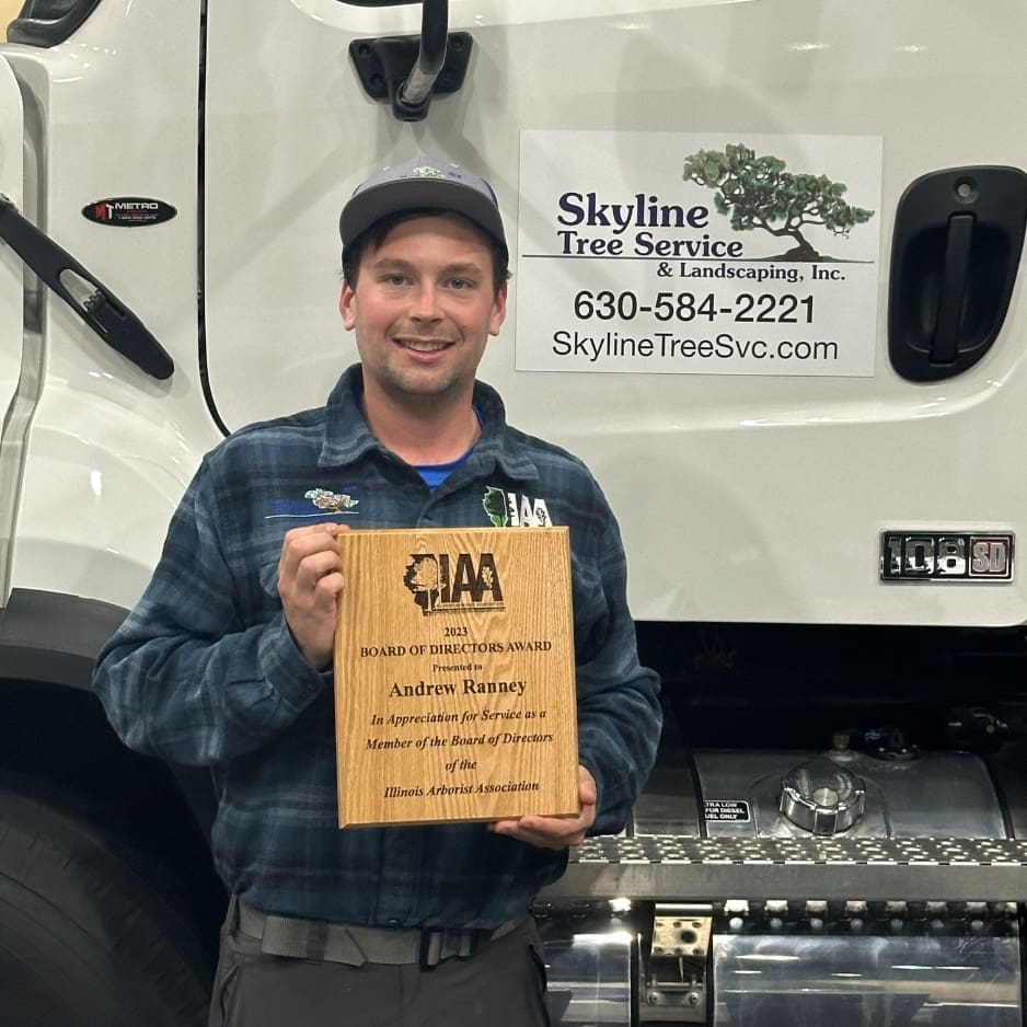 Man holding an award plaque, smiling outdoors.