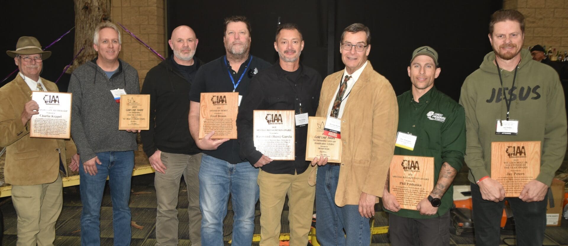 Eight men holding award plaques, smiling together.