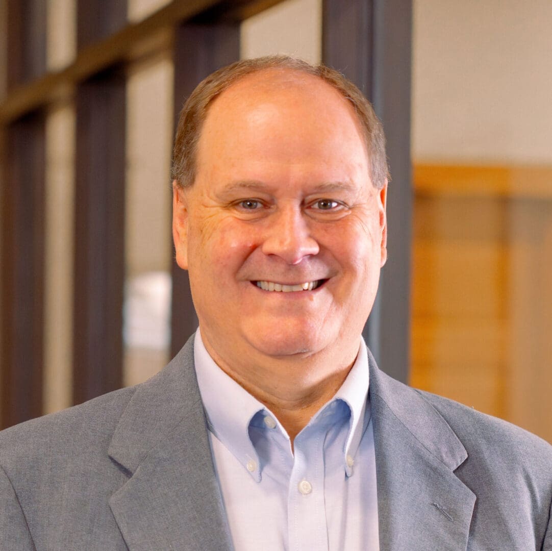 Smiling man in a light-colored suit.