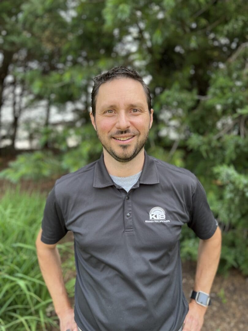 Man smiling outdoors in dark polo shirt.