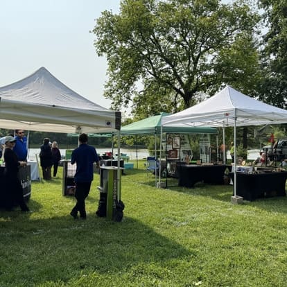 Outdoor vendor tents and booths on grassy lakeside