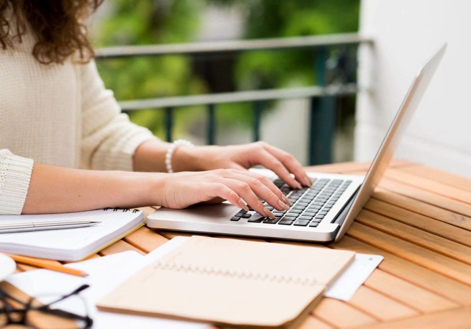 Person typing on laptop at outdoor table.